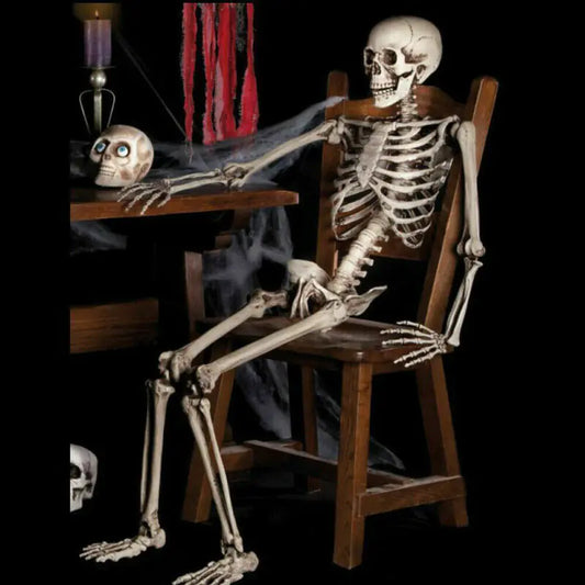 Skeletal figure sitting at a table with a candle and red fabric in a dark setting