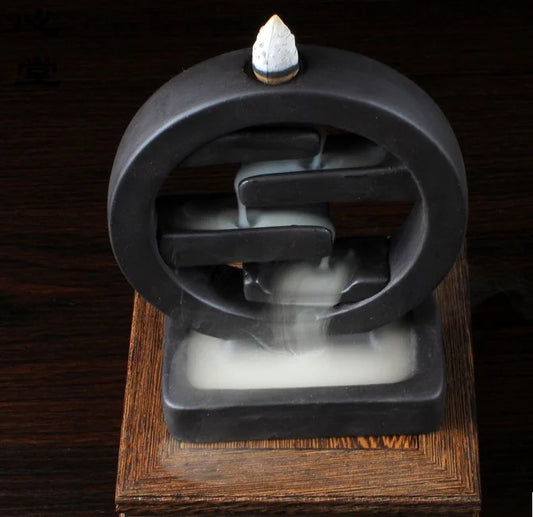 Black incense burner with a cone of incense on a wooden surface