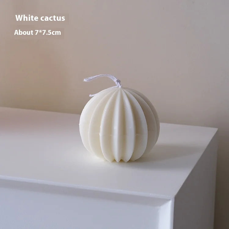 White cactus-shaped candle on a white surface with a plain background