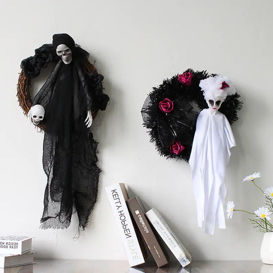 Halloween decorations including a black and white ghost figure and a wreath with flowers on a white surface.