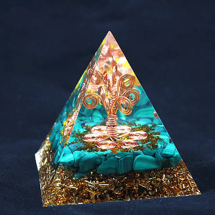 Pyramid-shaped decorative item with tree of life design on a dark background