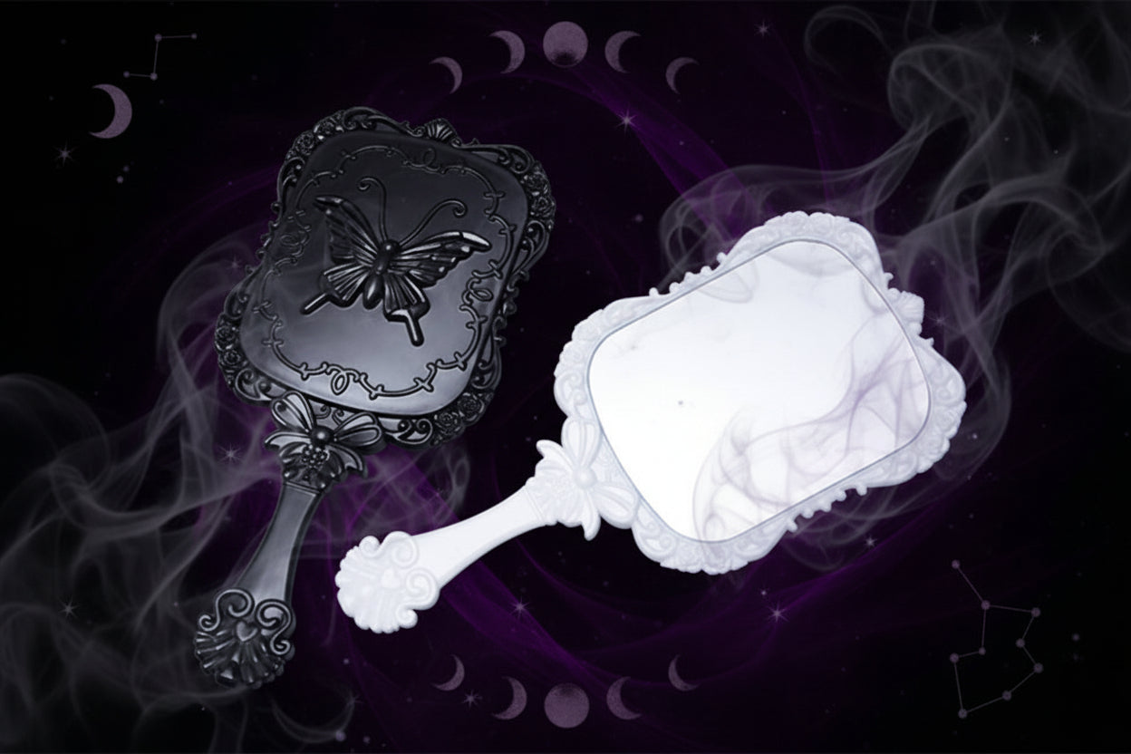 Black decorative hand mirror with butterfly design and white lace-edged mirror on a gray background