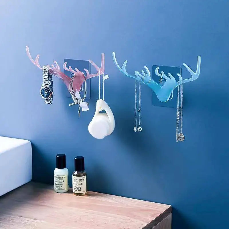 Two wall hooks with antler design on a blue wall, with items hanging from them.
