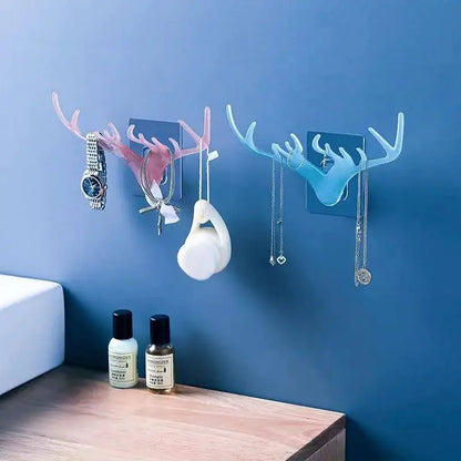 Two wall hooks with antler design on a blue wall, with items hanging from them.