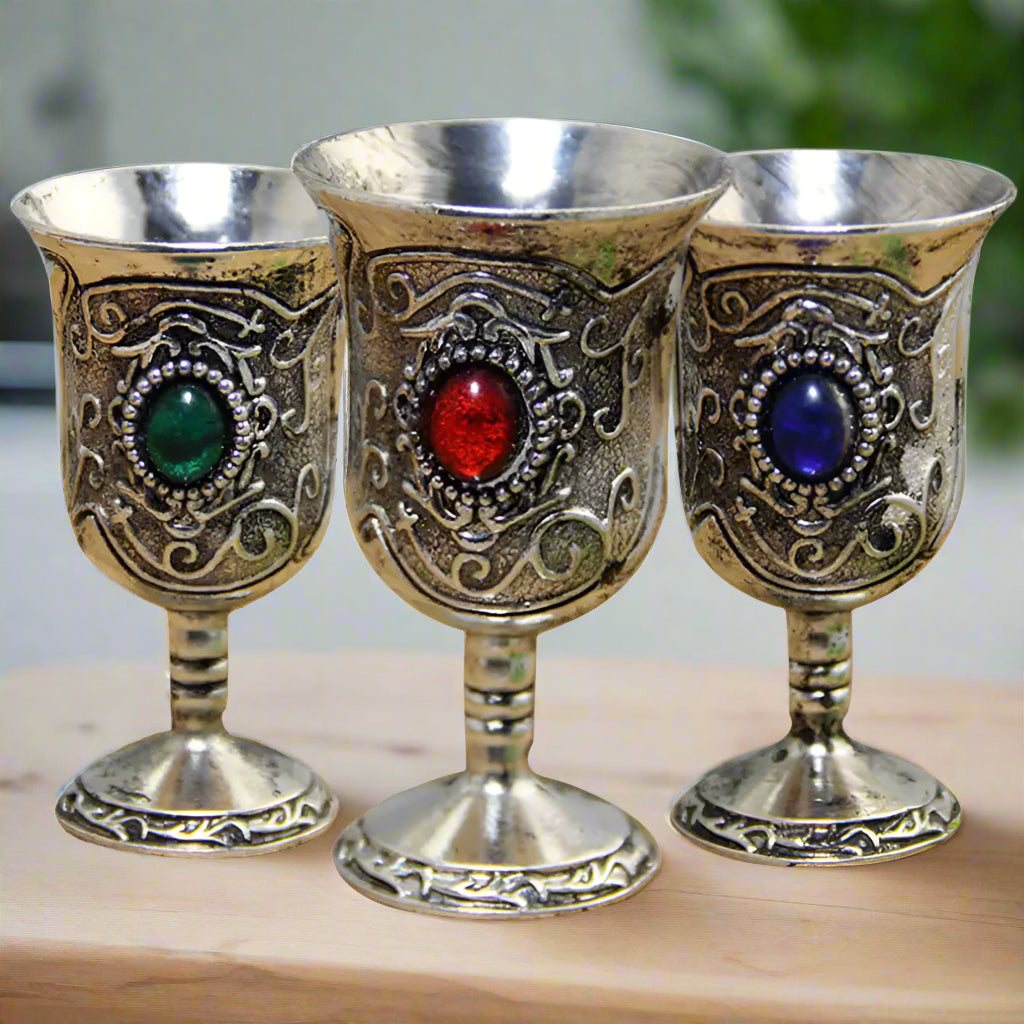 Three ornate goblets with colored gemstones on a white background