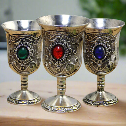 Three ornate goblets with colored gemstones on a white background