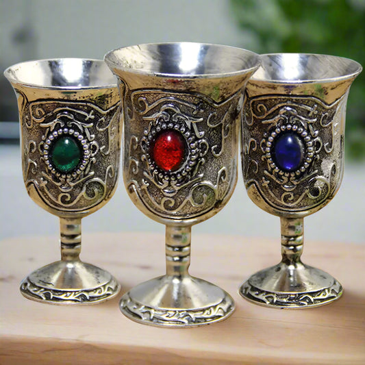 Three ornate goblets with colored gemstones on a white background