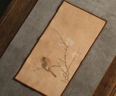 Decorative mat with a bird and branch design on a textured surface
