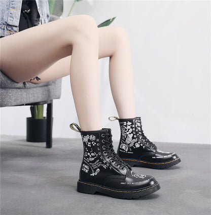 Black boots with white text and designs worn by a person sitting on a chair.