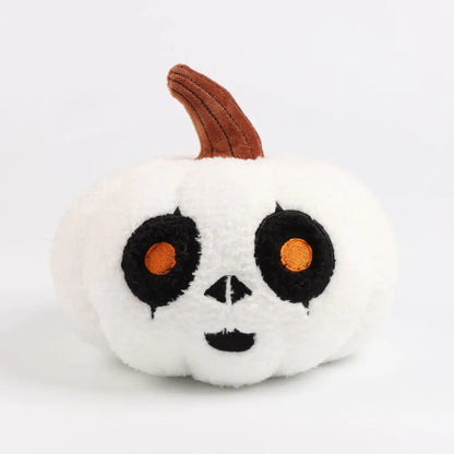 Plush toy shaped like a pumpkin with black eyes and a brown stem on a white background