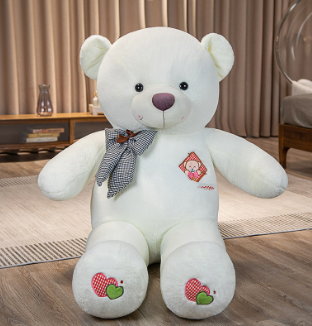 White teddy bear with a bow tie on a wooden floor