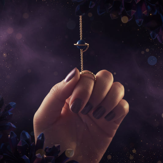 Hand holding a small blue stone on a string against a blurred green background