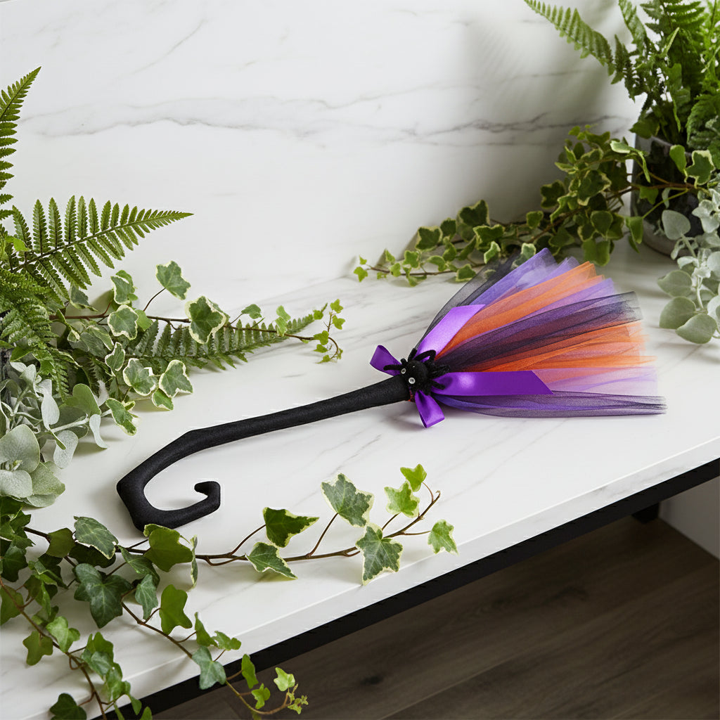 Halloween-themed decorative cane with a colorful tutu skirt and purple bow on a white background