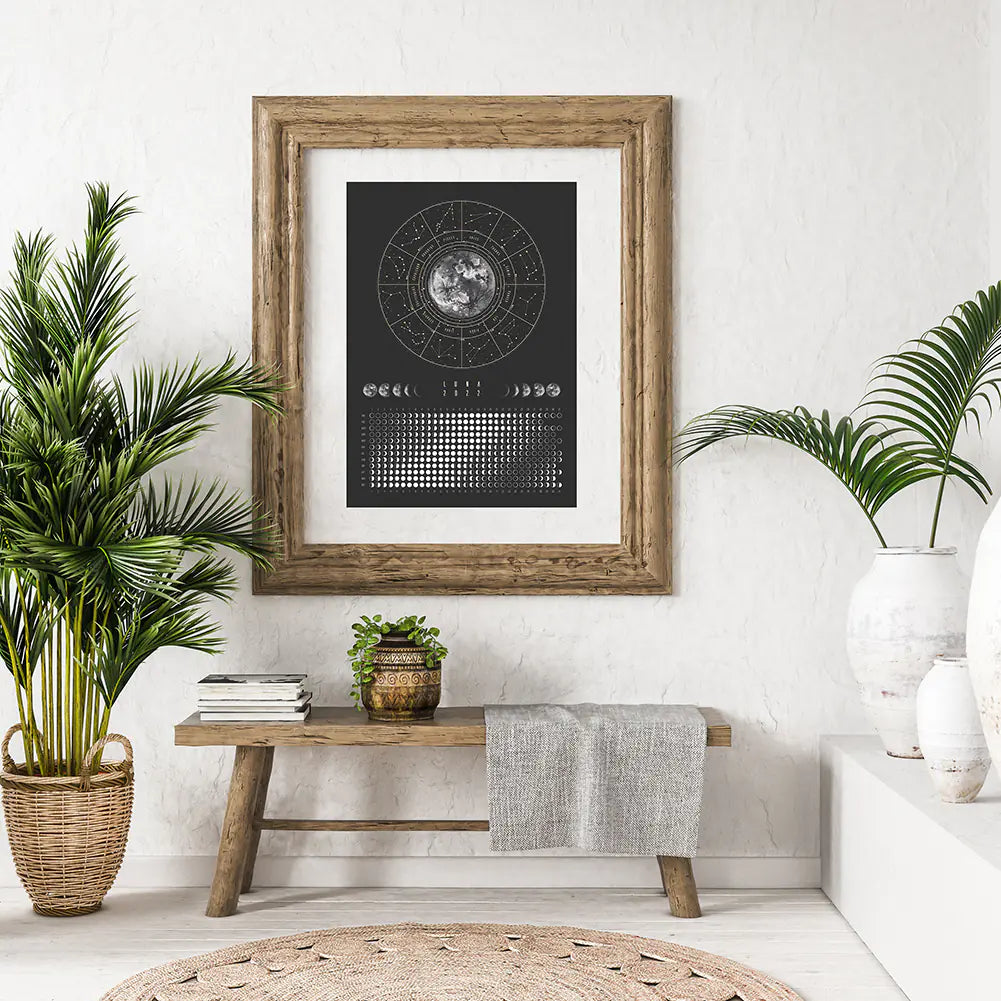 Framed black and white poster on a wall with plants and a wooden bench in a room.