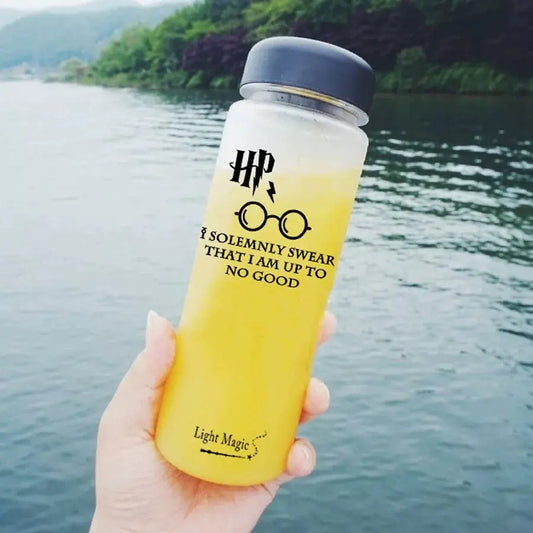 Yellow water bottle with HP branding held by a hand by a body of water