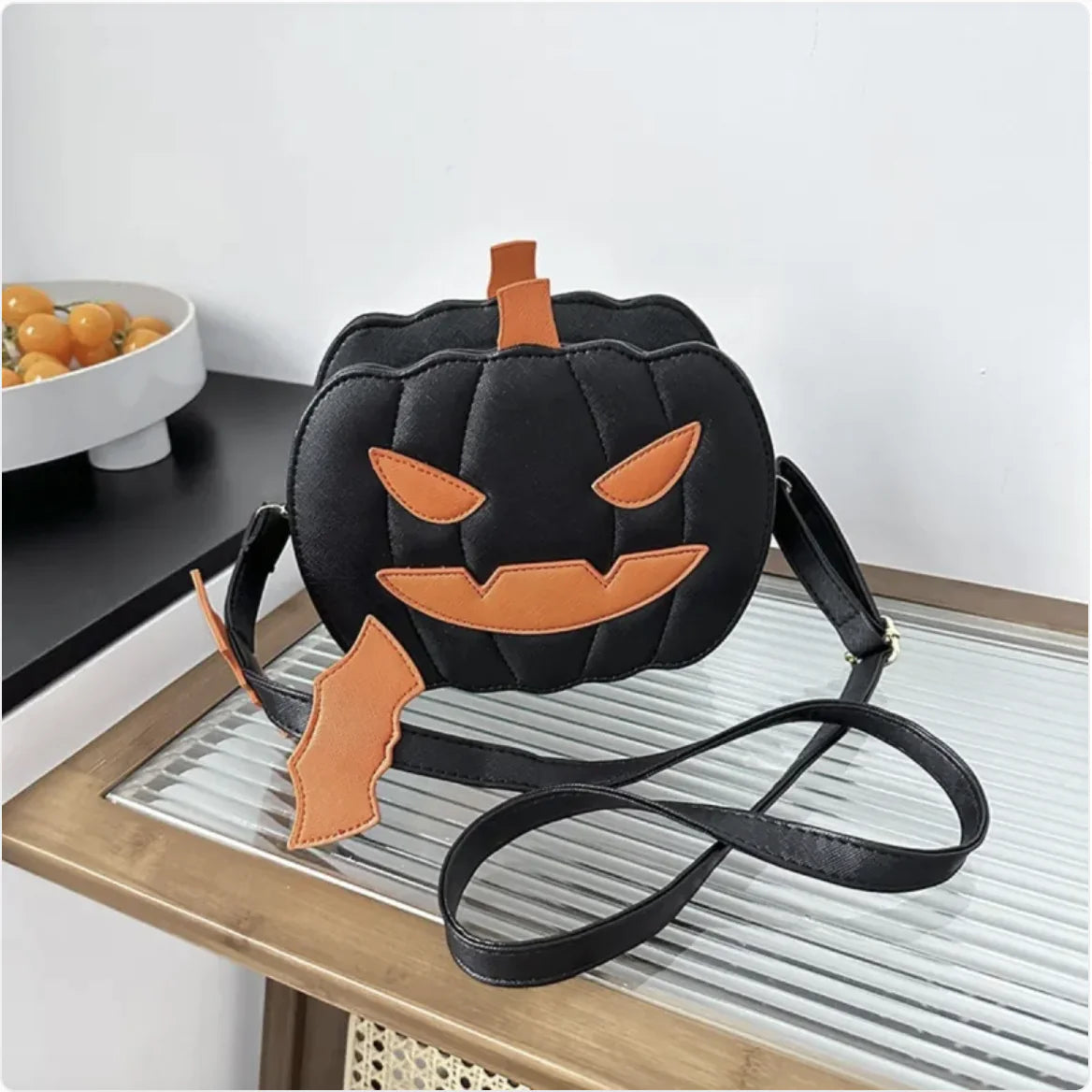 Black pumpkin-shaped bag with orange accents on a wooden surface