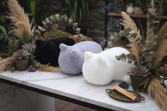 Three cat-shaped cushions in black, gray, and white on a white background
