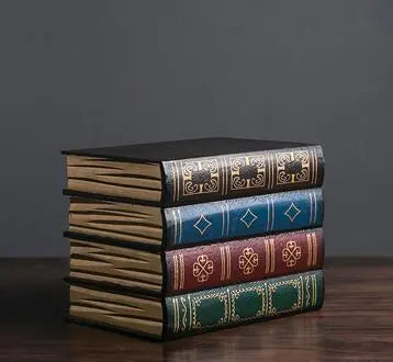 Stack of ornately bound books on a dark surface with a dark background