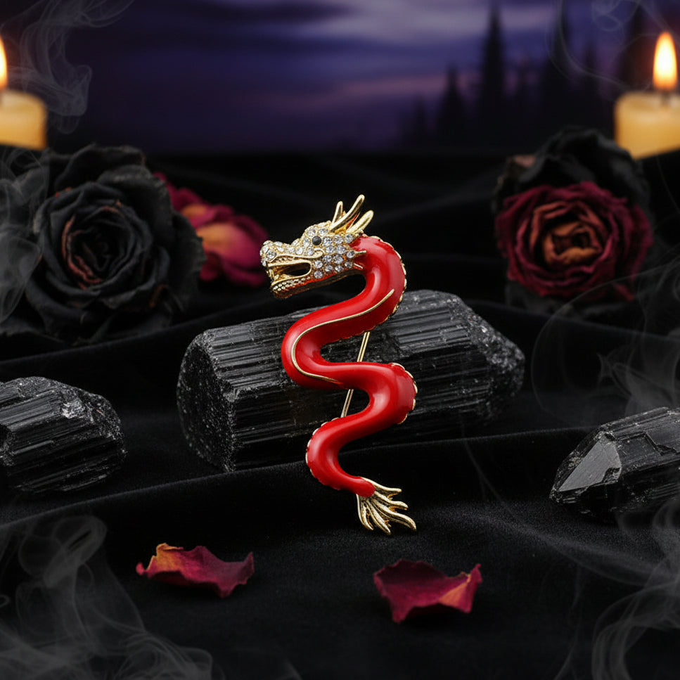 Red dragon brooch with gold accents on a dark stone surface