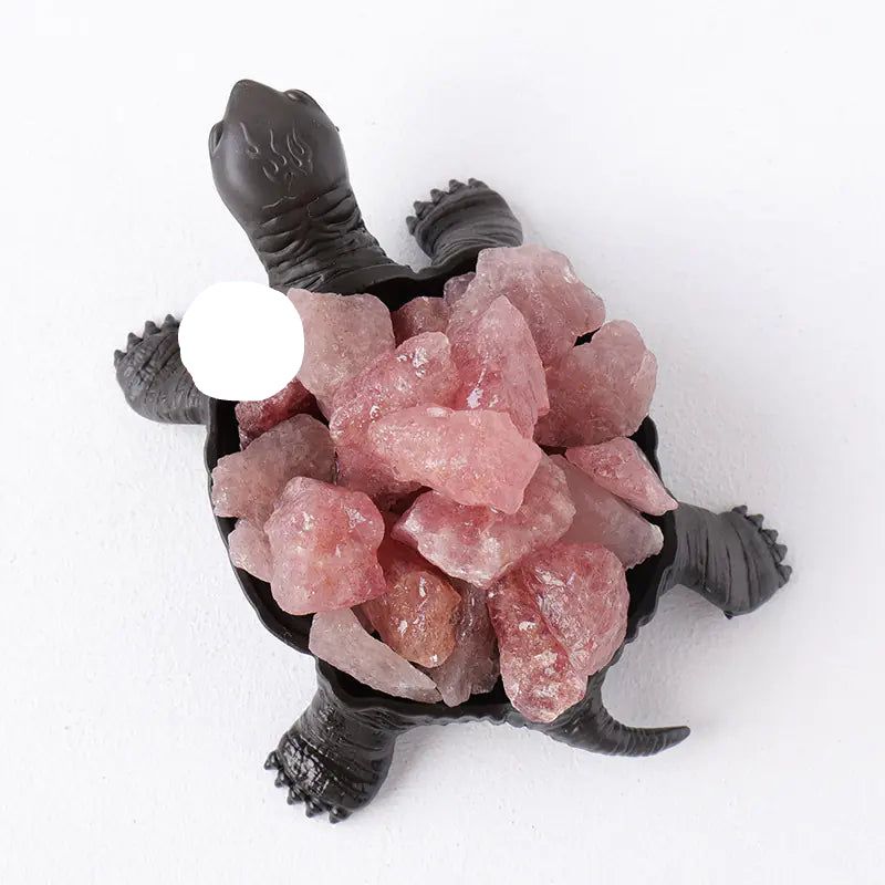 Tortoise figurine with pink crystals on a white background