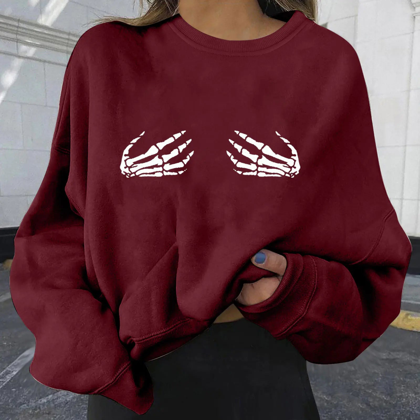 Maroon sweatshirt with skeleton hand design worn by a person.