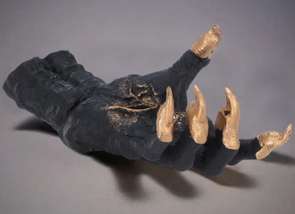 Black glove with gold claws on a gray background