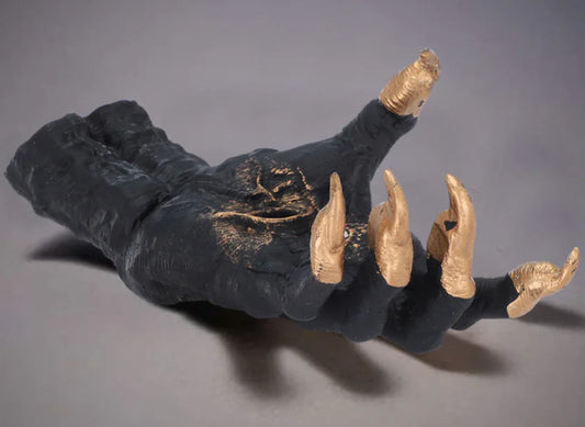 Black glove with gold claws on a gray background