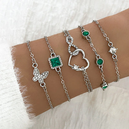 Silver bracelets with green gemstones on a wrist against a white background