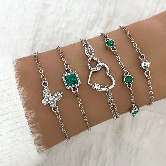 Silver bracelets with green gemstones on a wrist against a white background