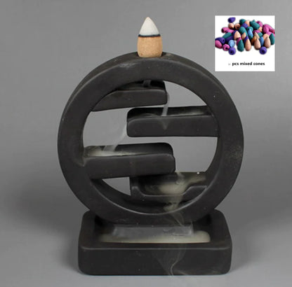 Black circular incense burner with a single incense cone on a gray background, inset with colorful incense cones.