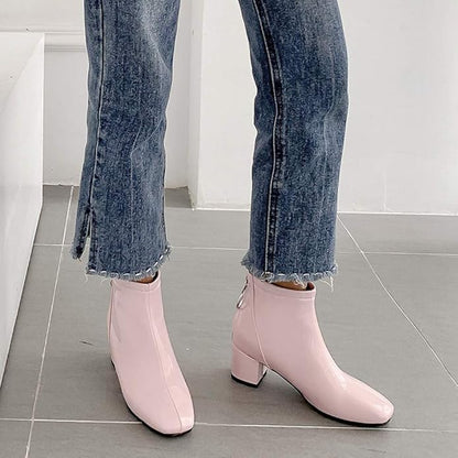 Pink ankle boots worn with blue jeans on a tiled floor.