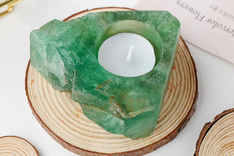 Tealight candle holder made of green crystal on a wooden surface