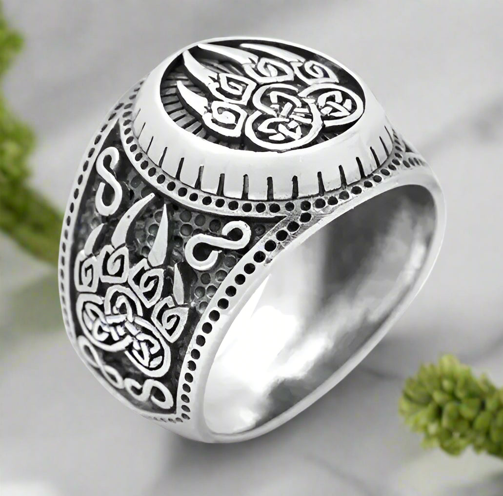 Silver ring with intricate Celtic knot design on a white background