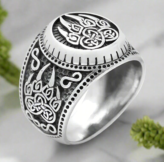 Silver ring with intricate Celtic knot design on a white background