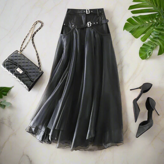 Black skirt with belt, black quilted handbag, and black high heels on a beige background