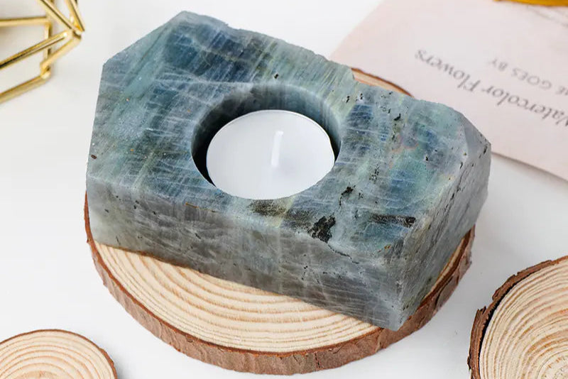 Candle holder made of natural stone on a white surface with wooden slices.
