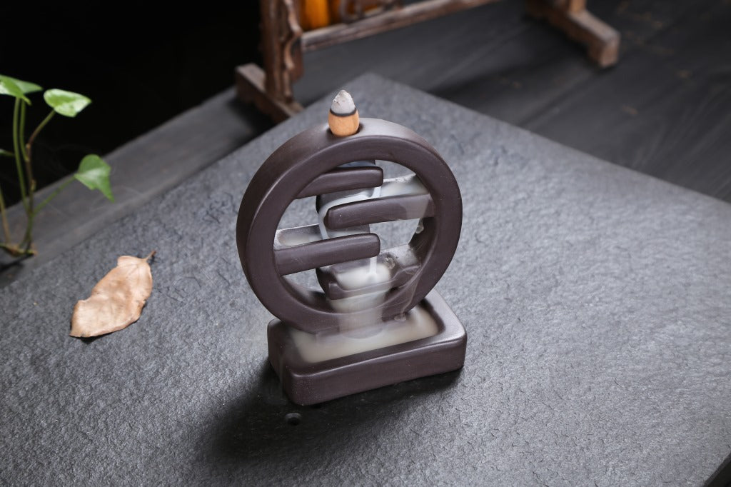 Ceramic incense burner with a small leaf on a dark surface