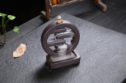 Ceramic incense burner with a small leaf on a dark surface