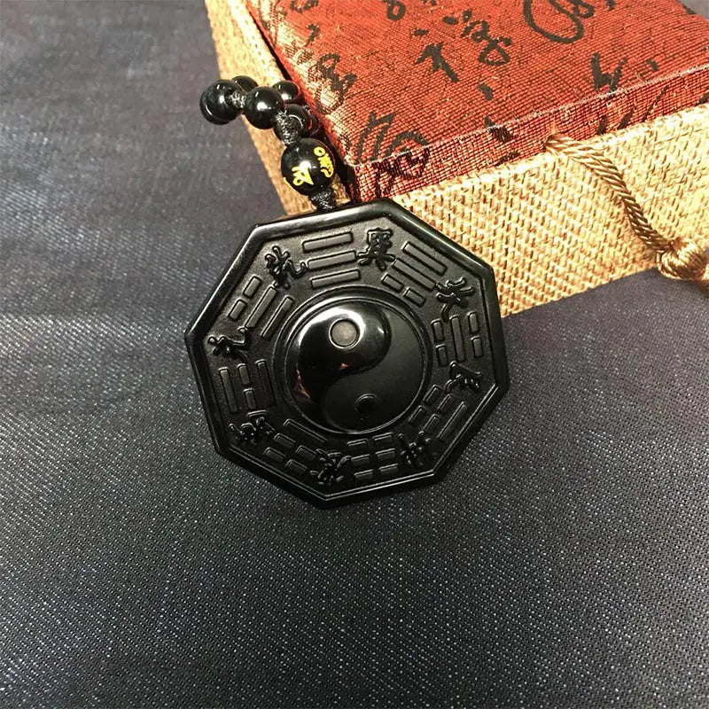 Black hexagonal pendant with intricate designs on a textured surface