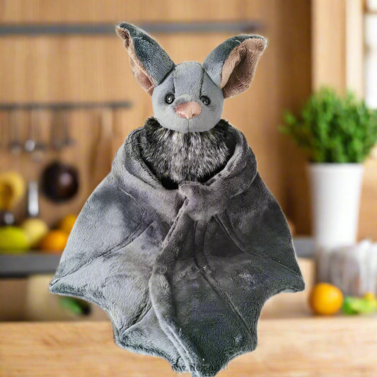 Plush bat toy wrapped in a gray blanket on a white background
