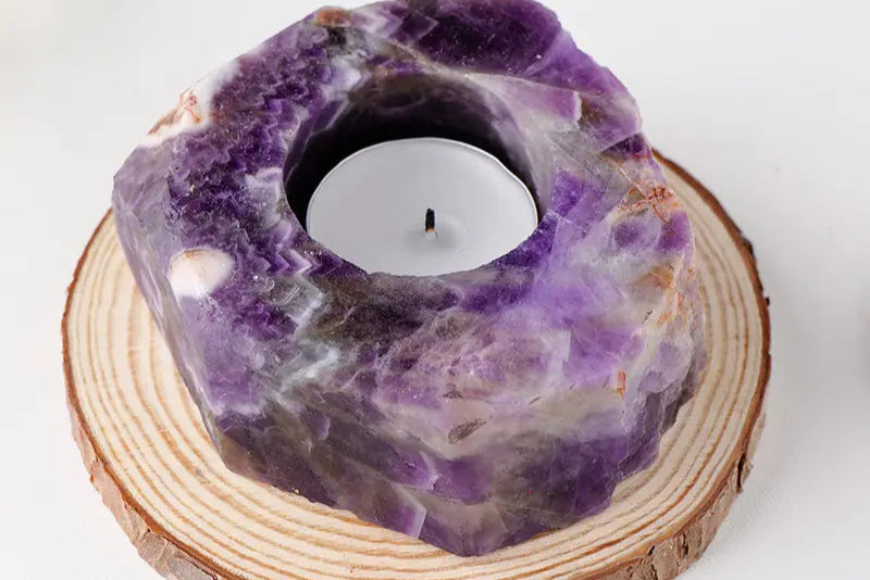 Purple crystal candle holder on a wooden base with a white background