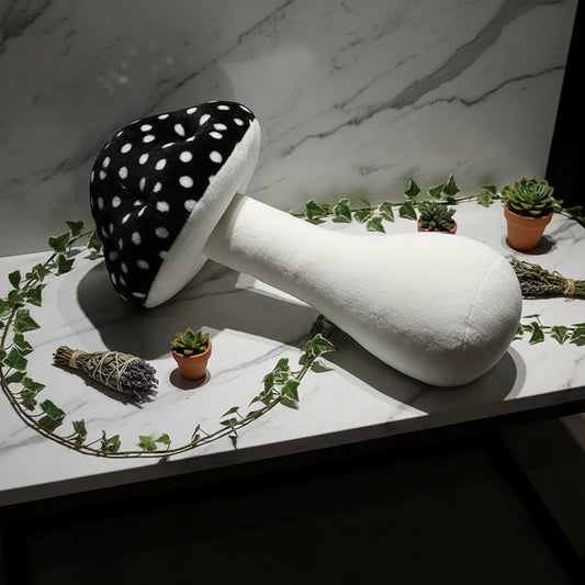 Black and white polka dot mushroom-shaped pillow on a surface with a newspaper.