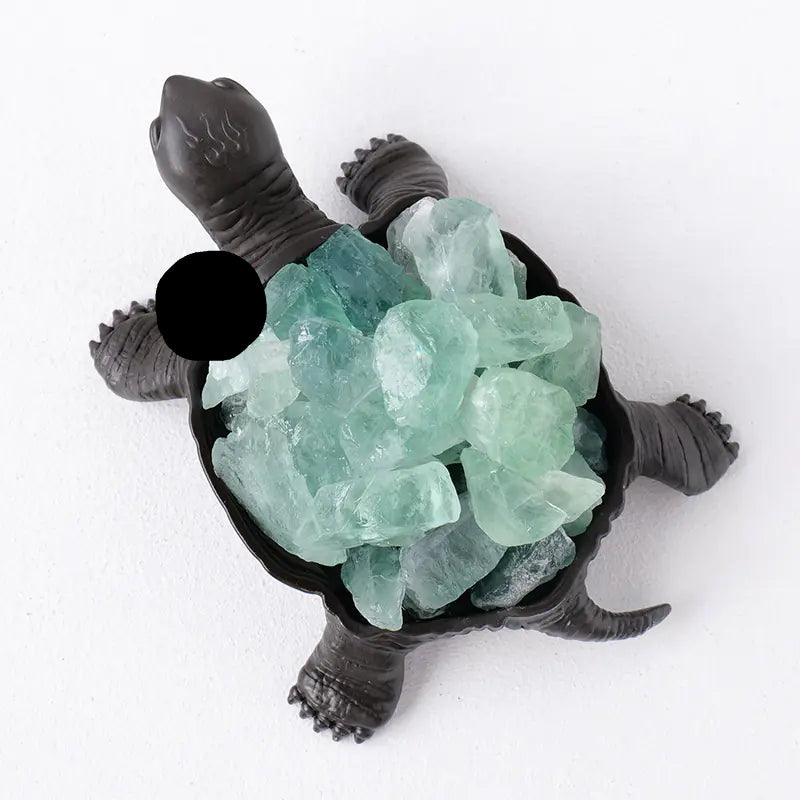 Tortoise figurine with green crystals on a white background