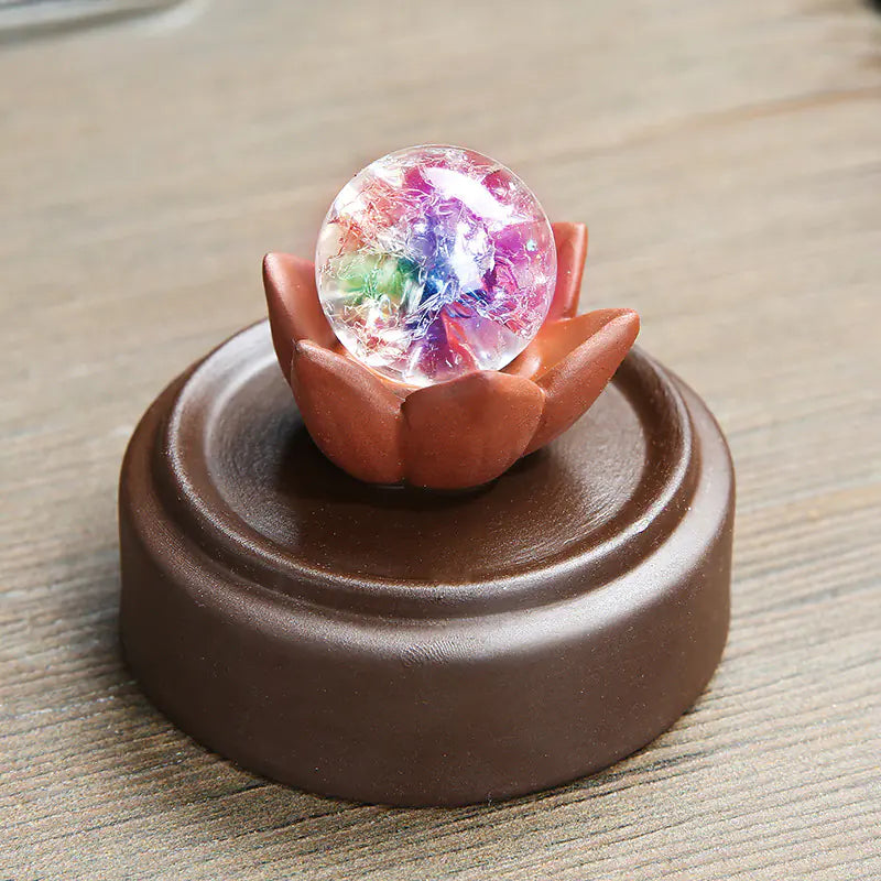 Decorative item with a colorful crystal ball inside a lotus flower on a brown base.