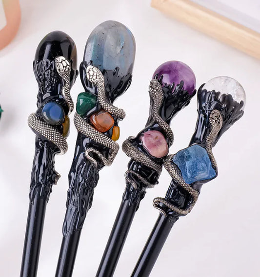 Set of four decorative crystal magic wands with gemstones on a white background