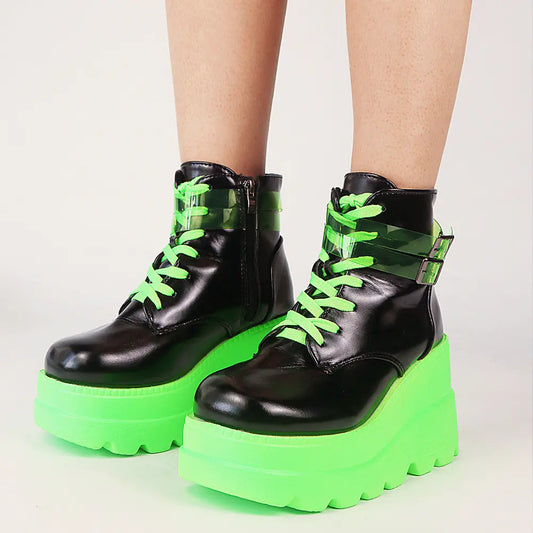 Black platform boots with green soles and laces on a light gray background
