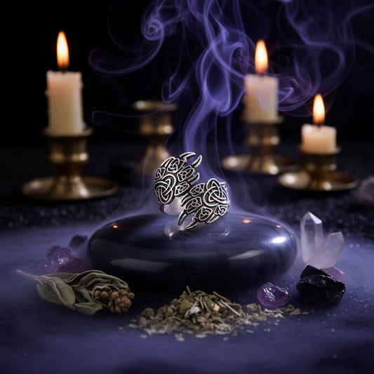 Silver ring with intricate designs on a black stone surface