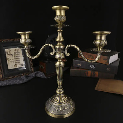 Bronze candelabrum on a dark surface with books and a picture frame in the background