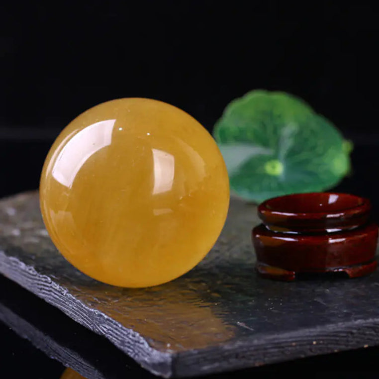 Yellow crystal ball on a dark surface with a blurred green leaf in the background