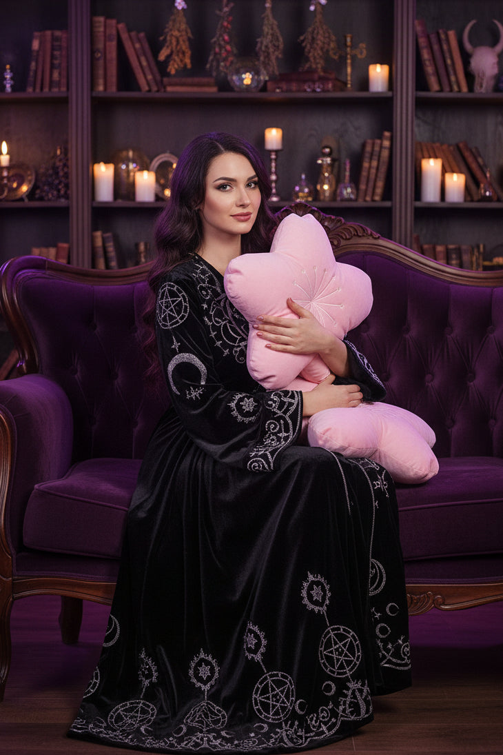 Woman holding a pink cherry blossom-shaped pillow in a cozy living room.